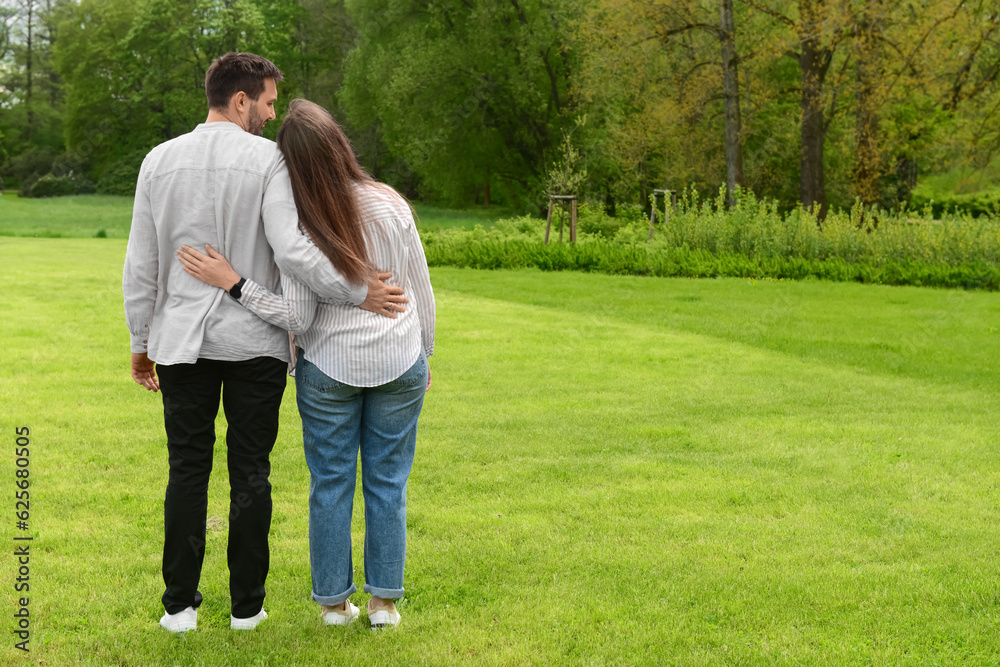 Beautiful loving couple hugging and walking in park on spring day