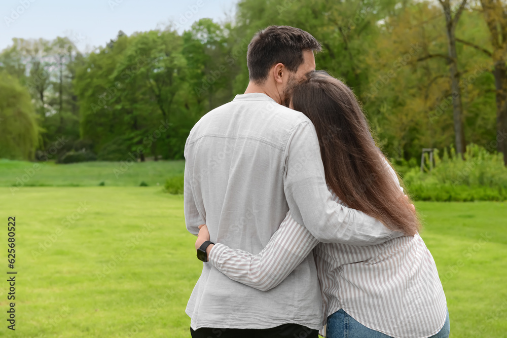 Beautiful loving couple hugging and walking in park on spring day