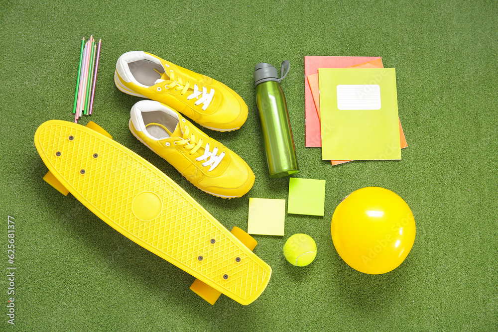 Sneakers with bottle of water, sport equipment and different stationery on color background