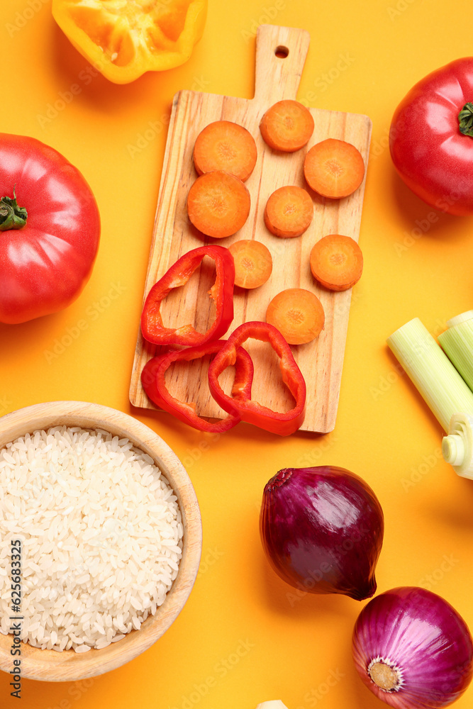 Bowl with rice and different fresh vegetables on orange background