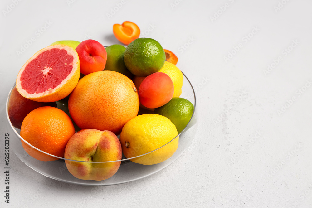 Bowl with different fresh fruits on grey background