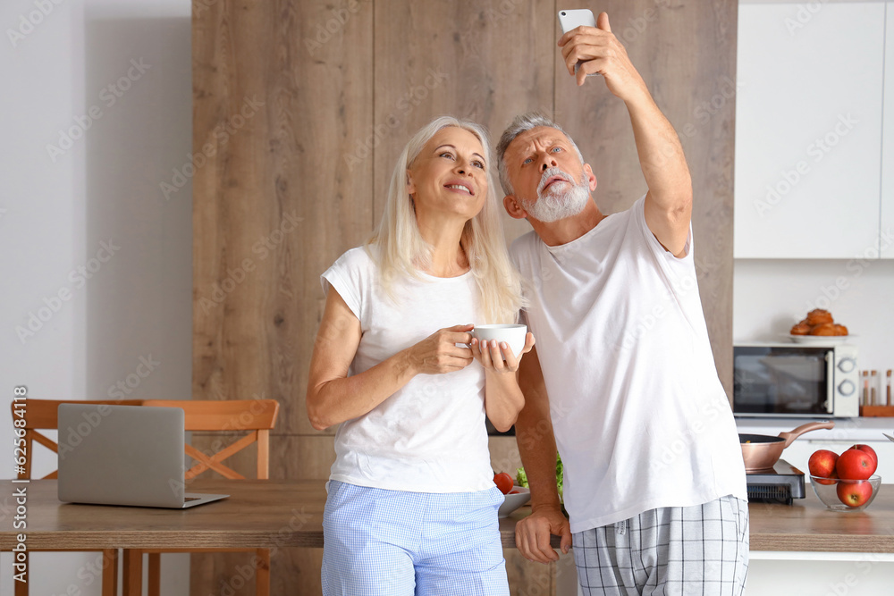 Mature couple taking selfie in kitchen