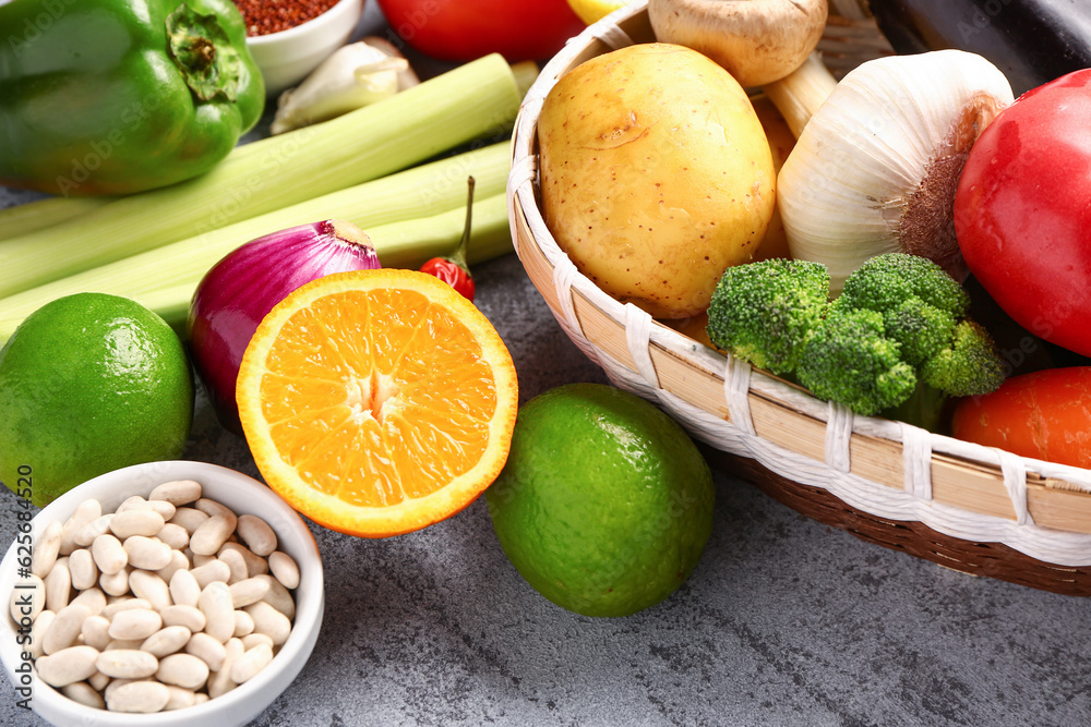 Wicker bowl with different fresh vegetables and cereals on blue background, closeup