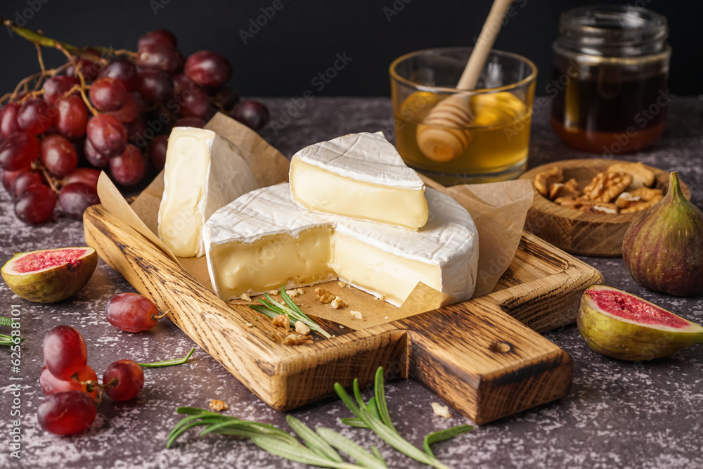 Wooden board with tasty Camembert cheese on table