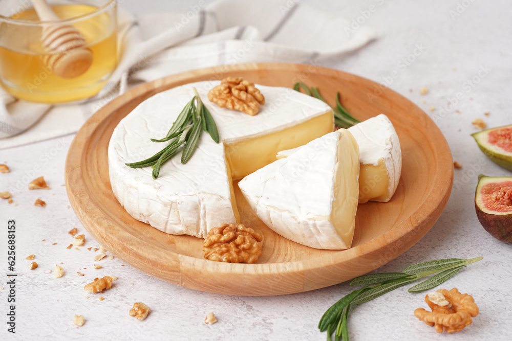 Plate with pieces of tasty Camembert cheese on light background