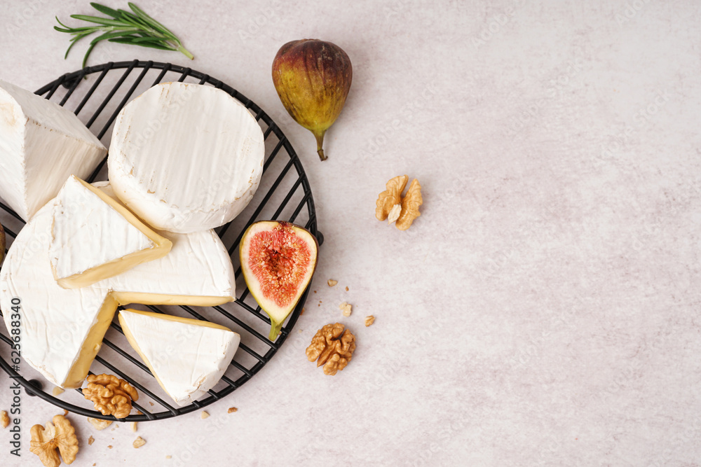 Grid with pieces of tasty Camembert cheese on light background