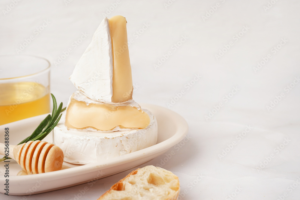 Plate with tasty Camembert cheese on light background