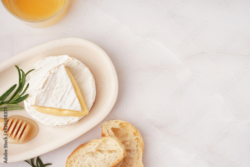 Plate with tasty Camembert cheese on light background