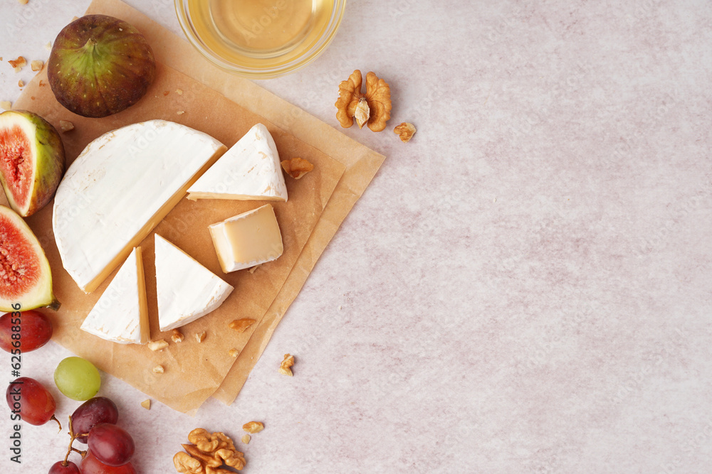 Pieces of tasty Camembert cheese with nuts and fruits on light background