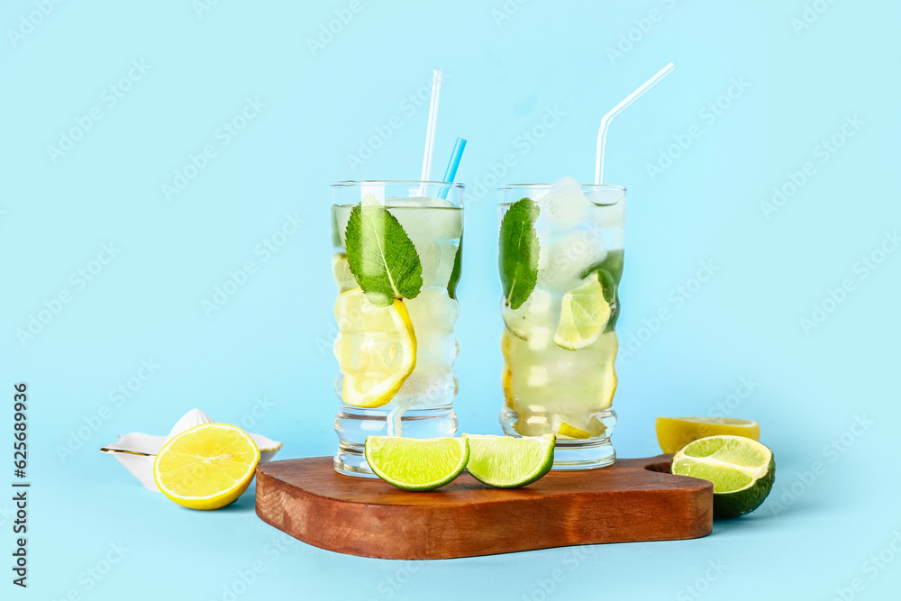 Wooden board with glasses of cold mojito and citrus fruits on color background