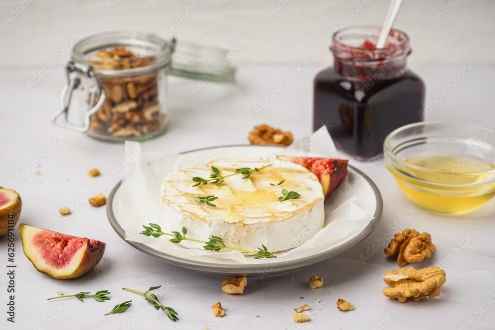 Plate of tasty baked Camembert cheese on grey background