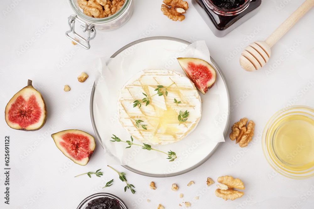 Plate of tasty baked Camembert cheese on grey background