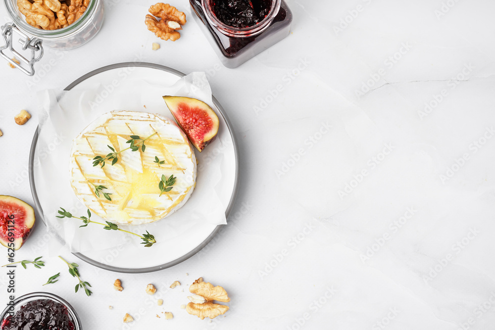 Plate of tasty baked Camembert cheese on grey background