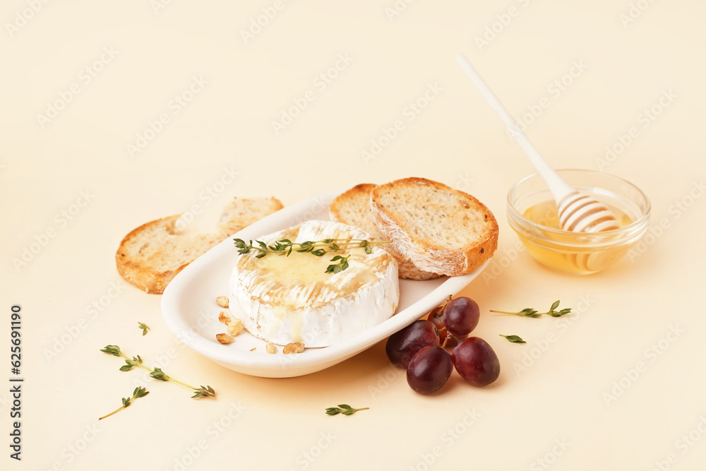 plate of tasty baked Camembert cheese with bread on yellow background