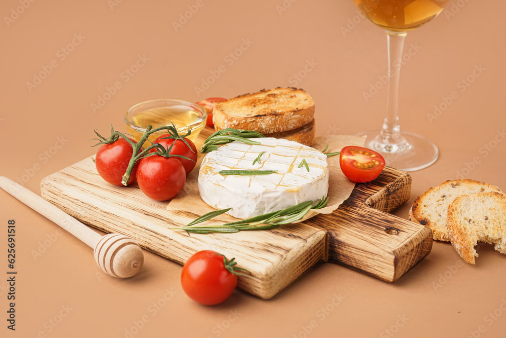 Wooden board with tasty baked Camembert cheese on brown background