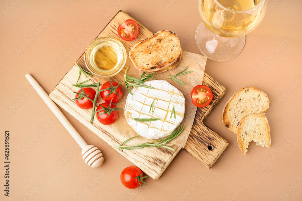 Wooden board with tasty baked Camembert cheese on brown background