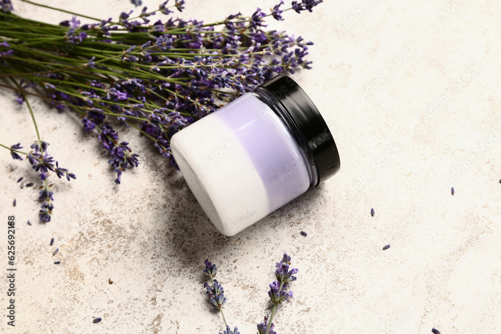 Jar of cosmetic product and lavender flowers on light background