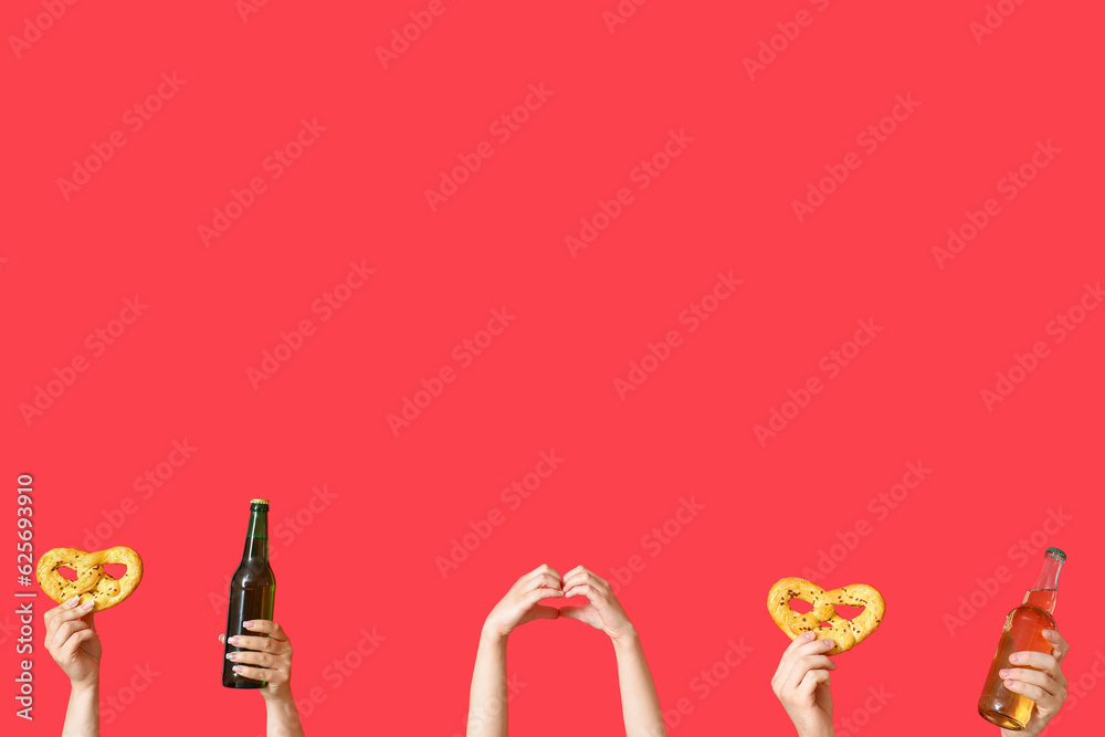 Many hands with bottles of cold beer and pretzels on red background