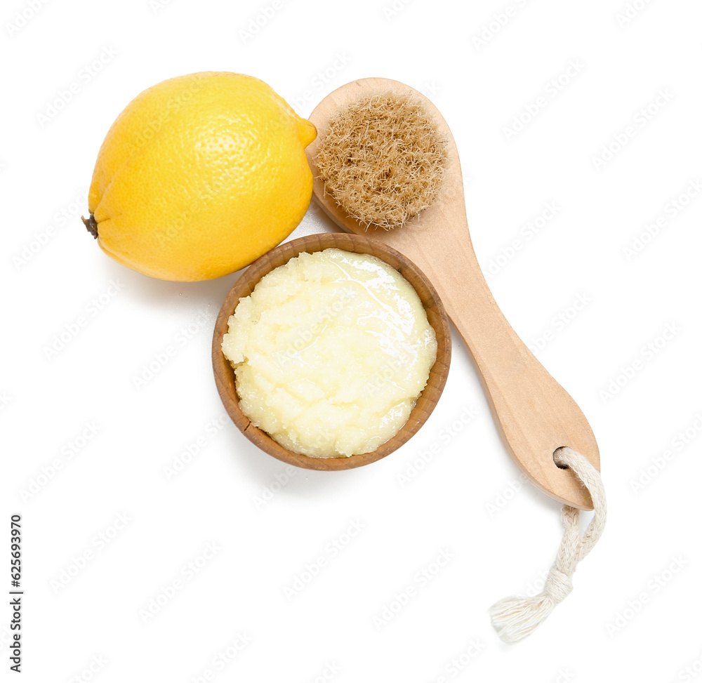 Bowl of lemon body scrub with massage brush isolated on white background