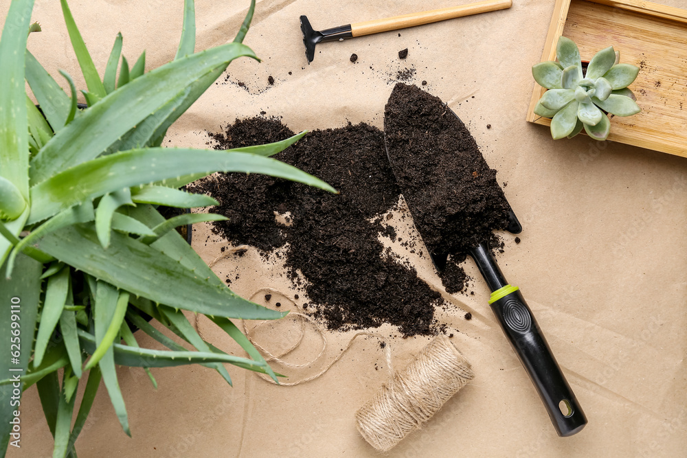 Shovel with soil and plants on craft paper background