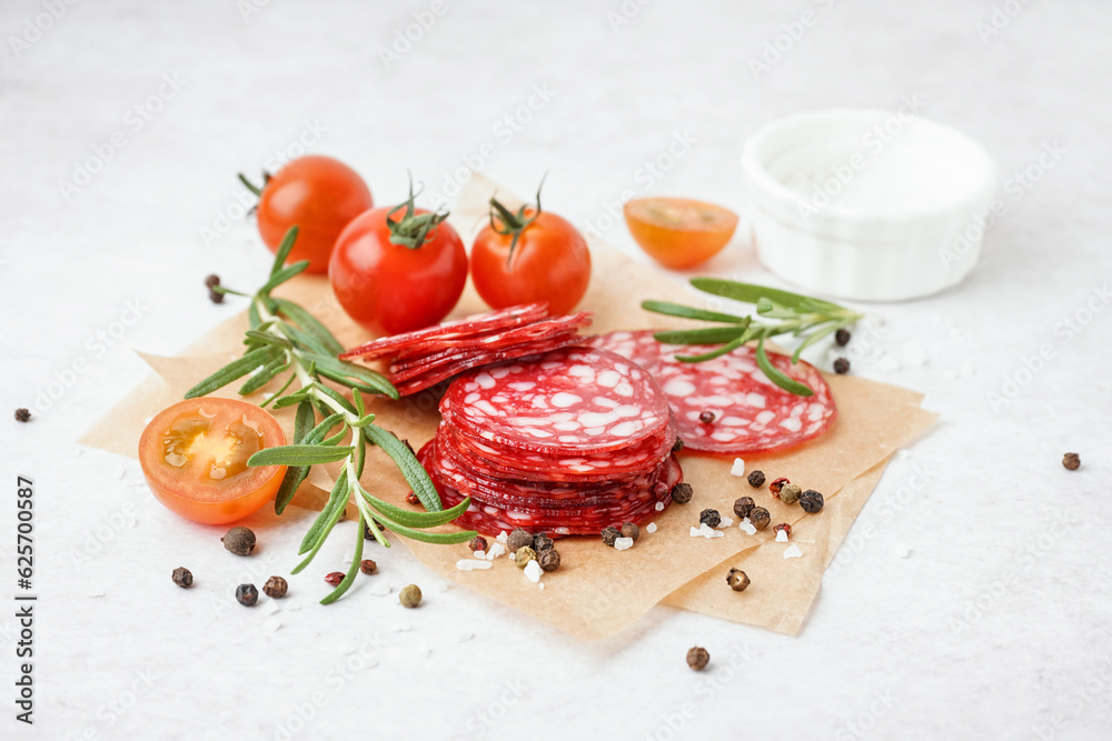 Slices of tasty salami on light background