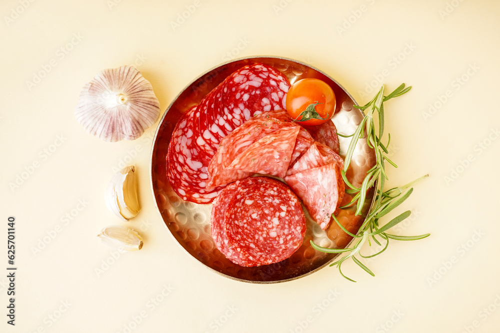 Plate with slices of tasty salami on yellow background