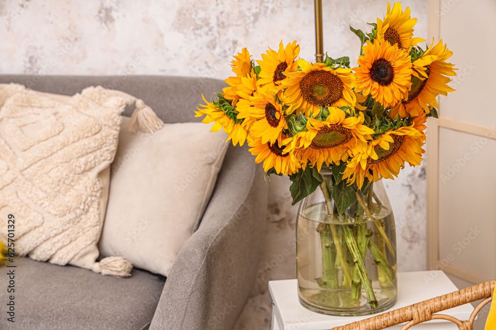 Vase with beautiful sunflowers on table in interior of light living room, closeup