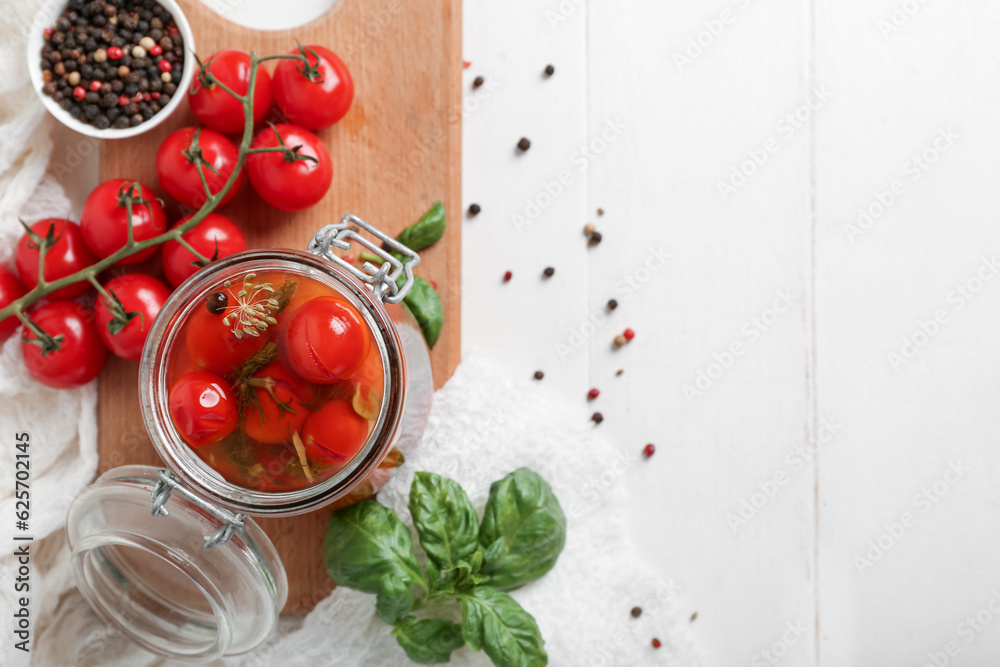 Jar with canned tomatoes and basil on white wooden table