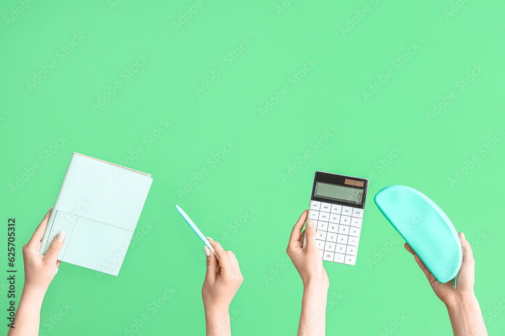 Female hands with school accessories on green background