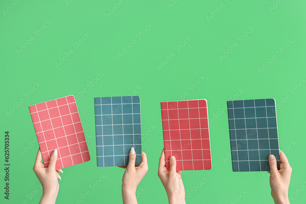 Female hands with notebooks on green background