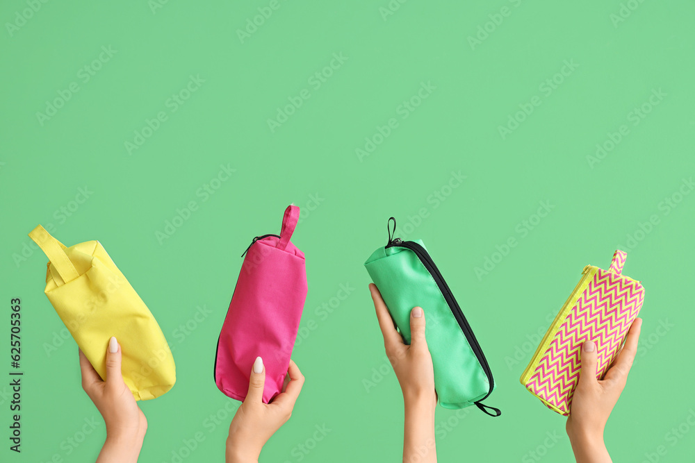 Female hands with pencil cases on green background