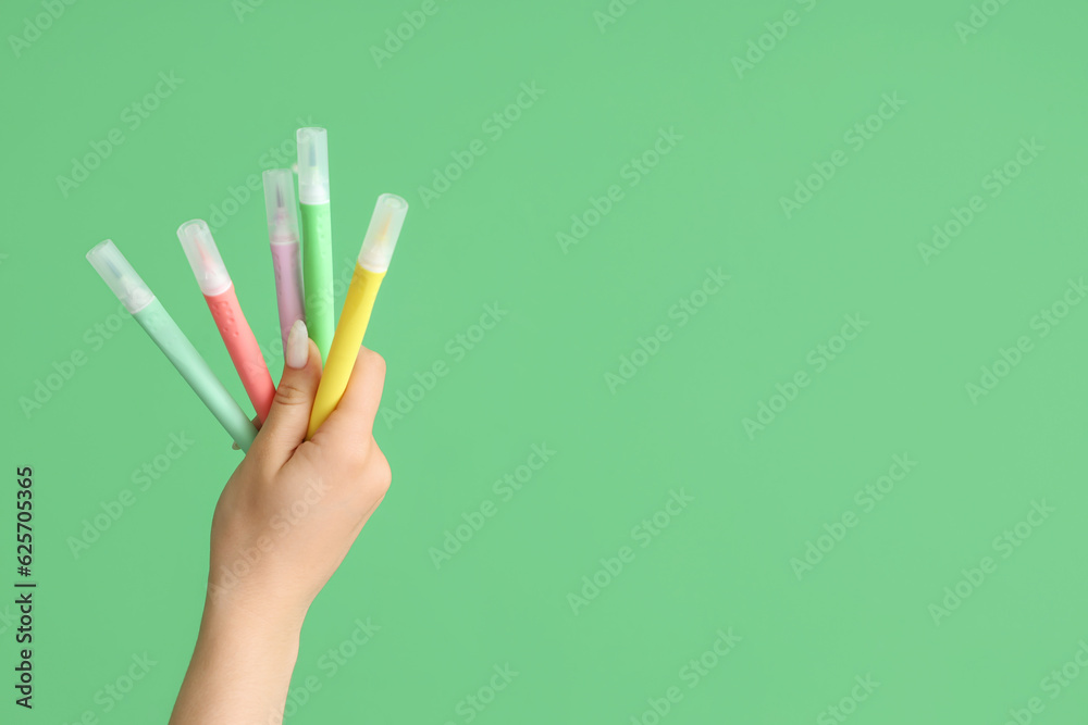 Female hand with felt tip pens on green background