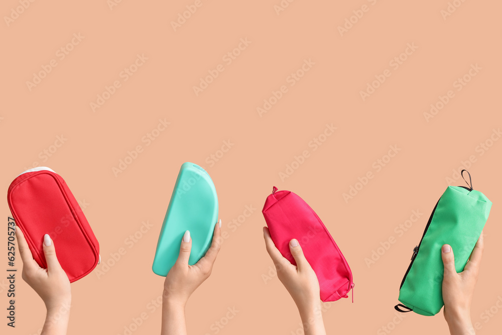 Female hands with pencil cases on beige background