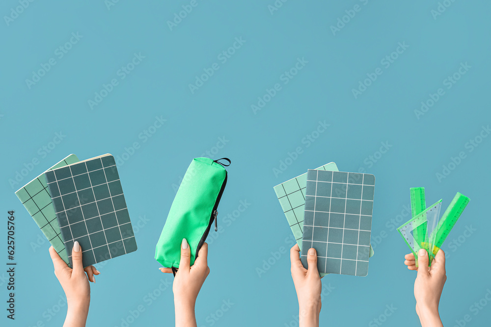 Female hands with school supplies on blue background