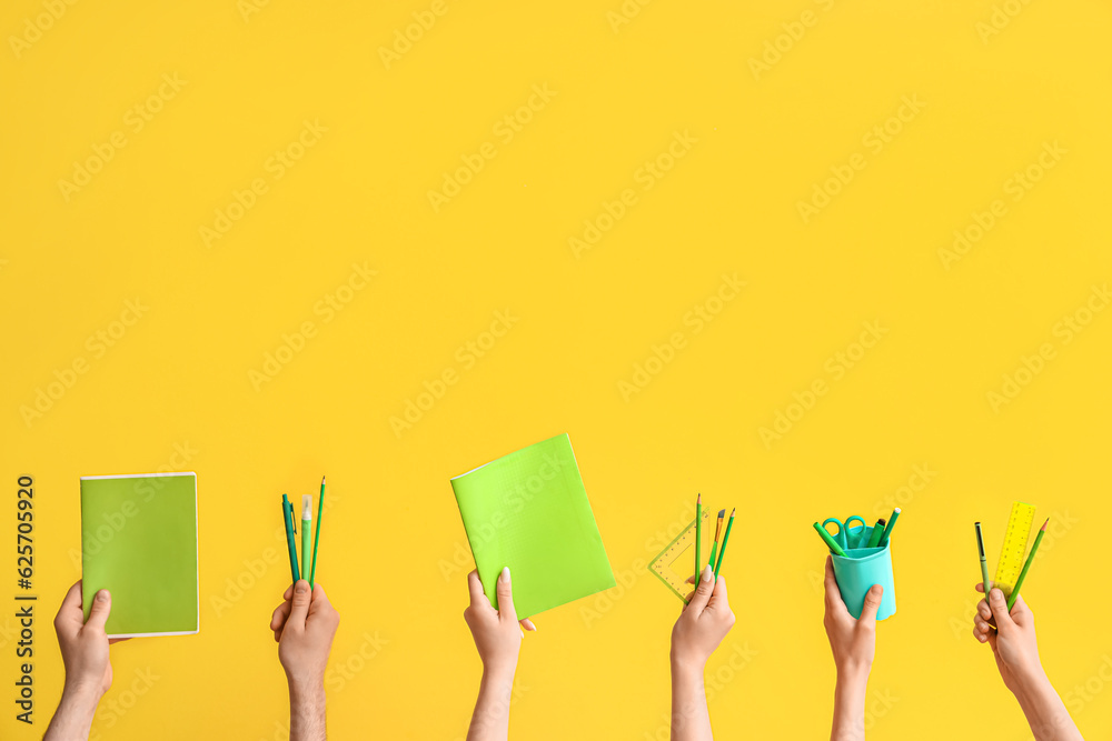 Hands with school supplies on yellow background