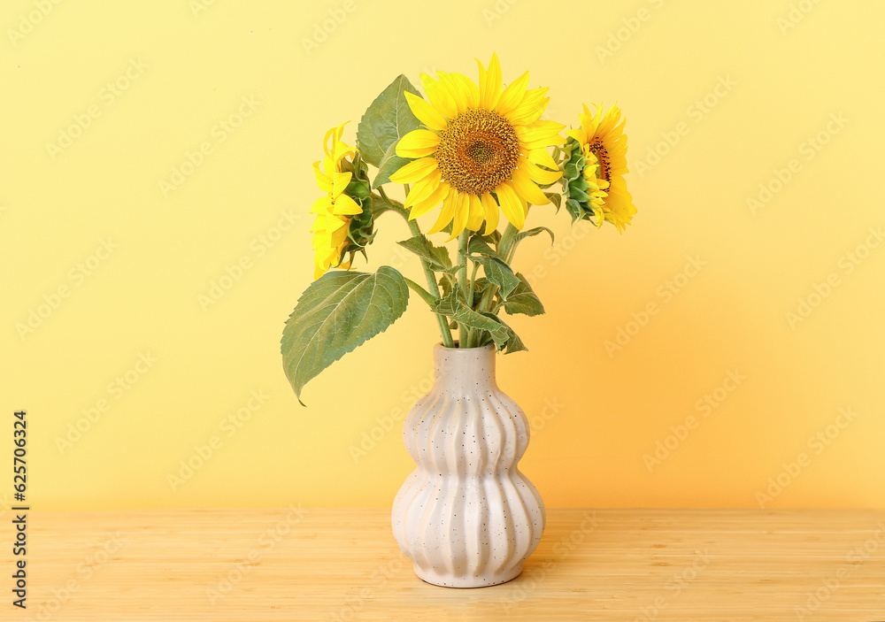 Vase with sunflowers on table near color wall