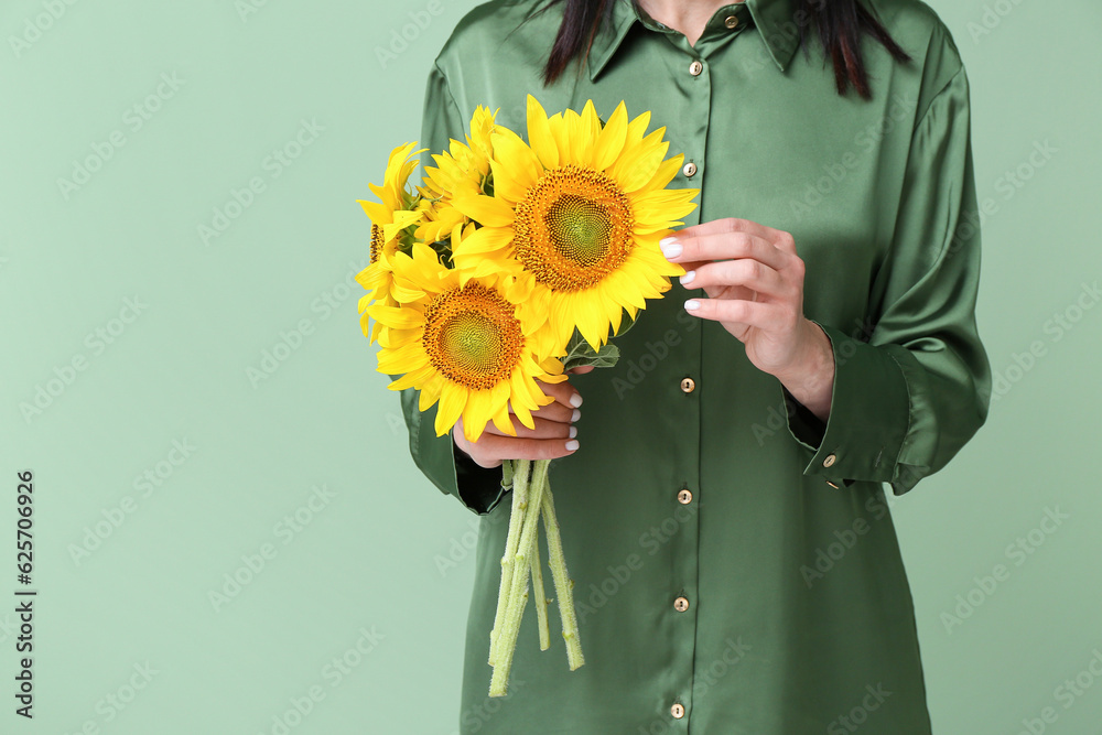 Young woman with beautiful sunflowers on green background, closeup