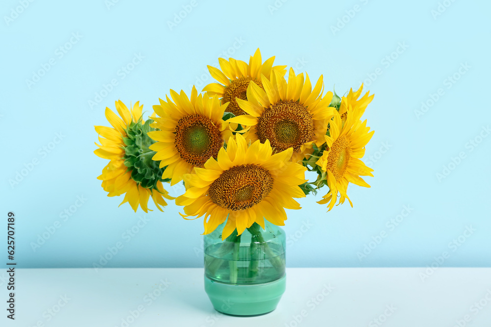 Vase with sunflowers on shelf near blue wall