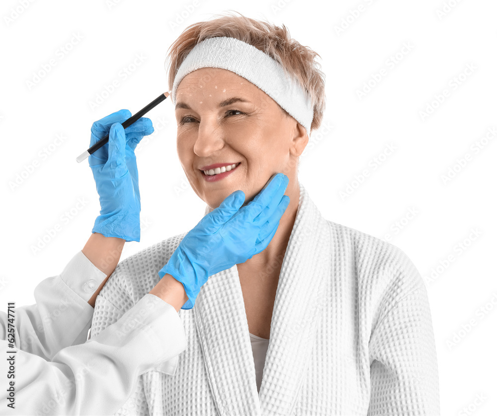 Beautician marking forehead of mature woman for filler injection on white background, closeup