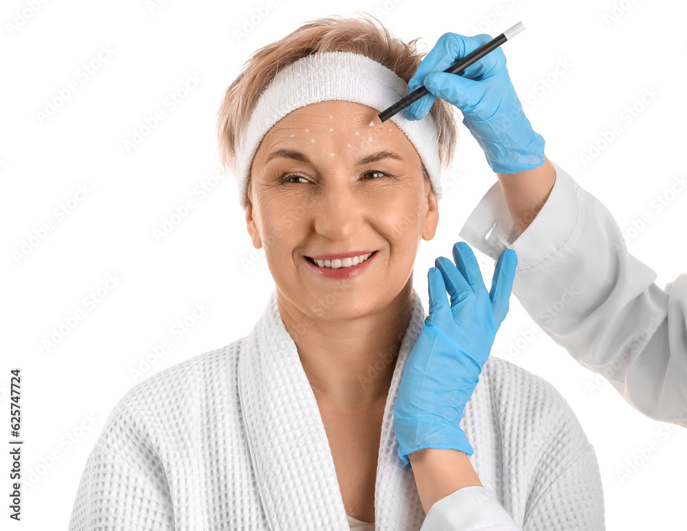 Beautician marking forehead of mature woman for filler injection on white background, closeup