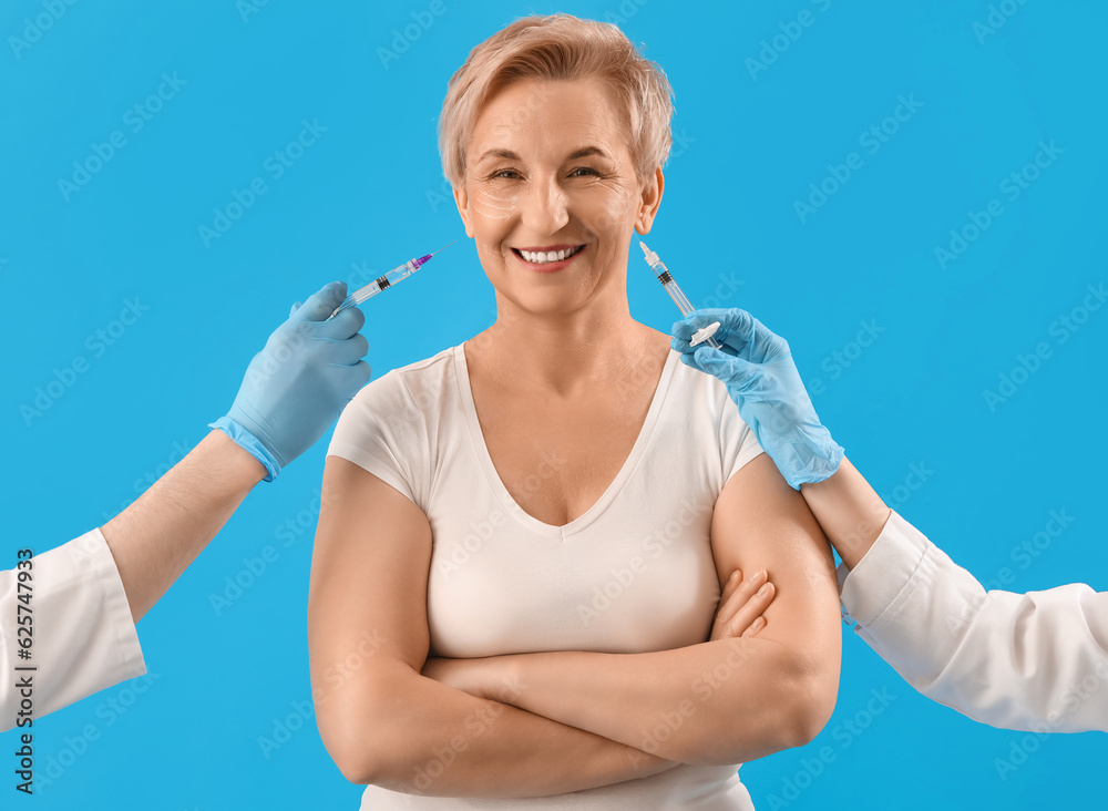 Mature woman and beauticians hands with filler injections on blue background