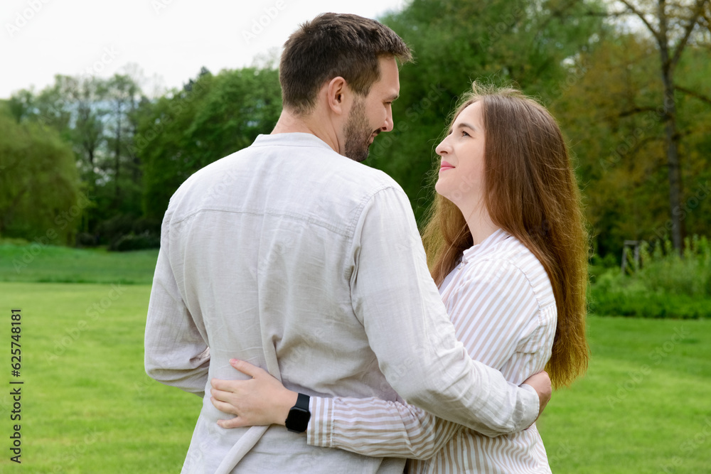 Beautiful loving couple hugging and walking in park on spring day