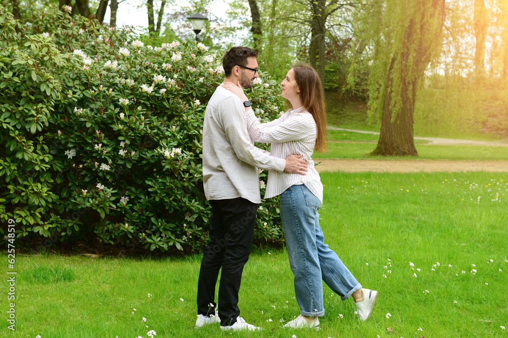 Beautiful happy loving couple hugging in park on spring day