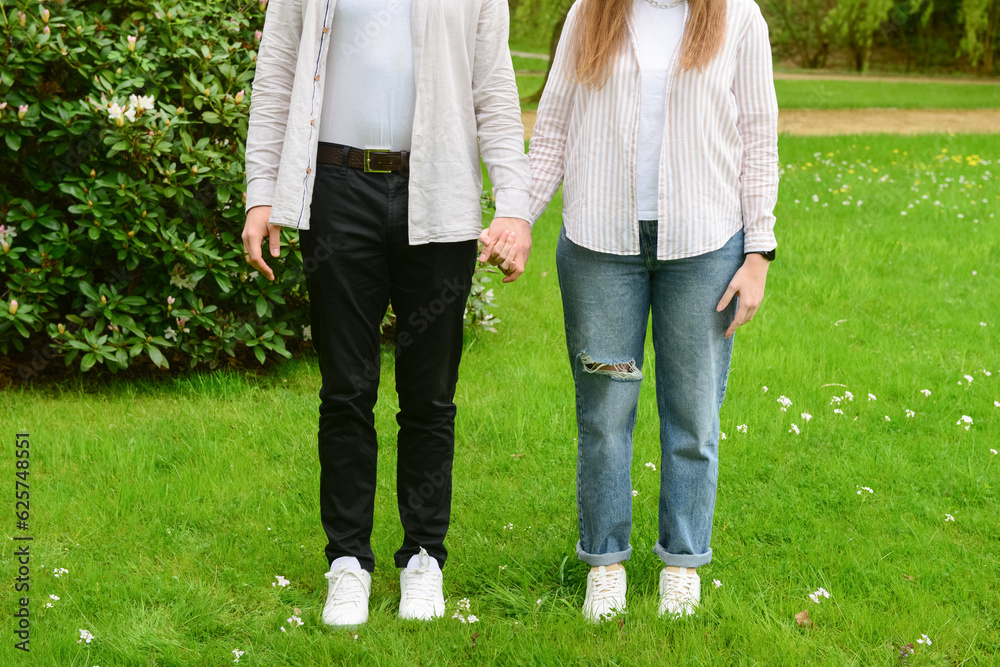 Beautiful happy loving couple holding hands in park on spring day