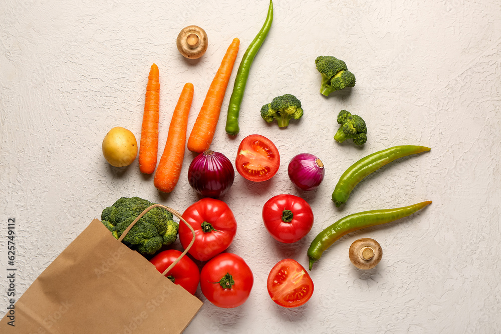 Paper bag with different fresh vegetables on white background