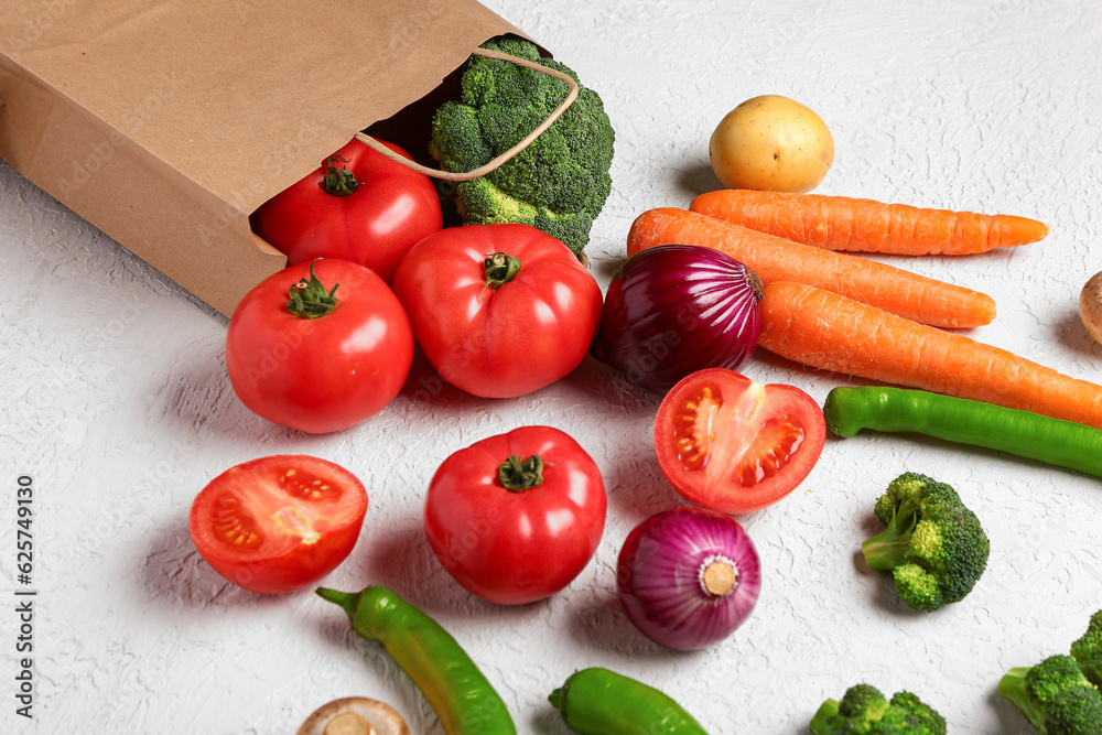 Paper bag with different fresh vegetables on white background