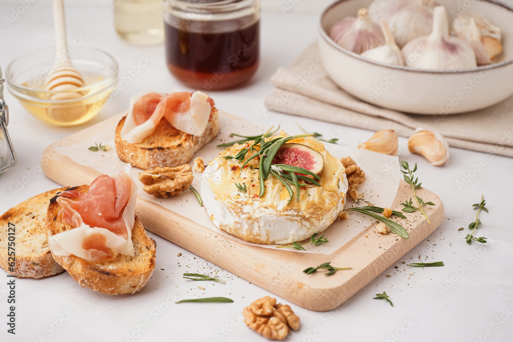 Wooden board with tasty baked Camembert cheese on grey background