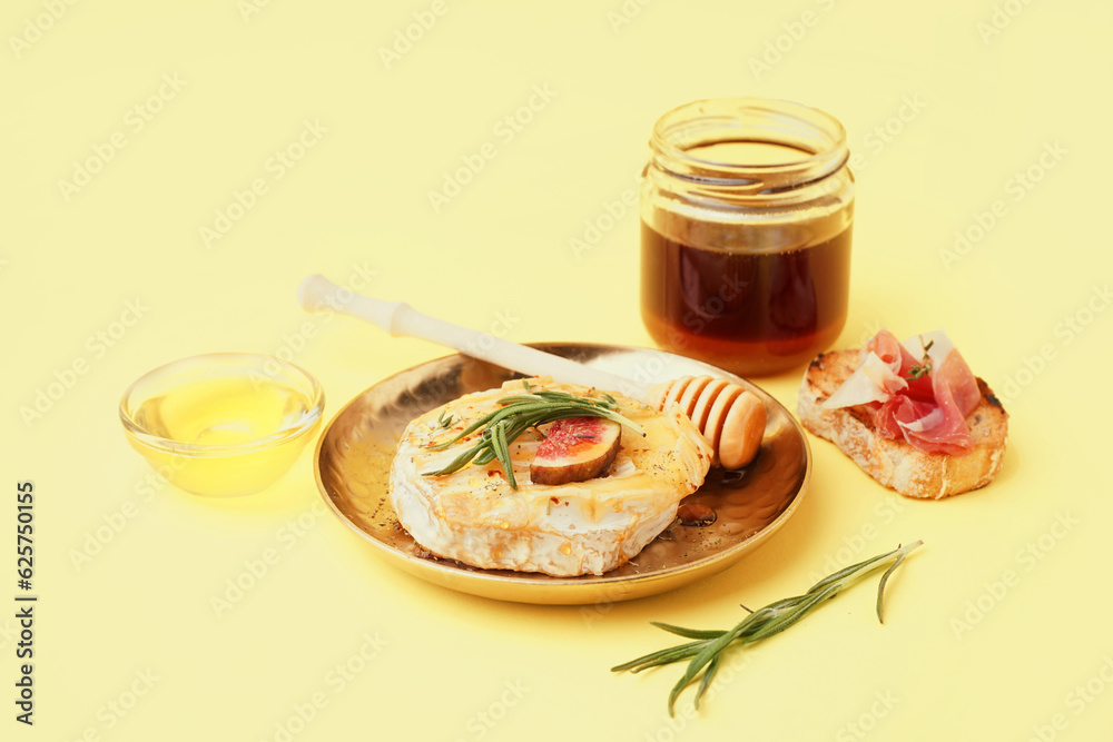 Plate with tasty baked Camembert cheese on yellow background