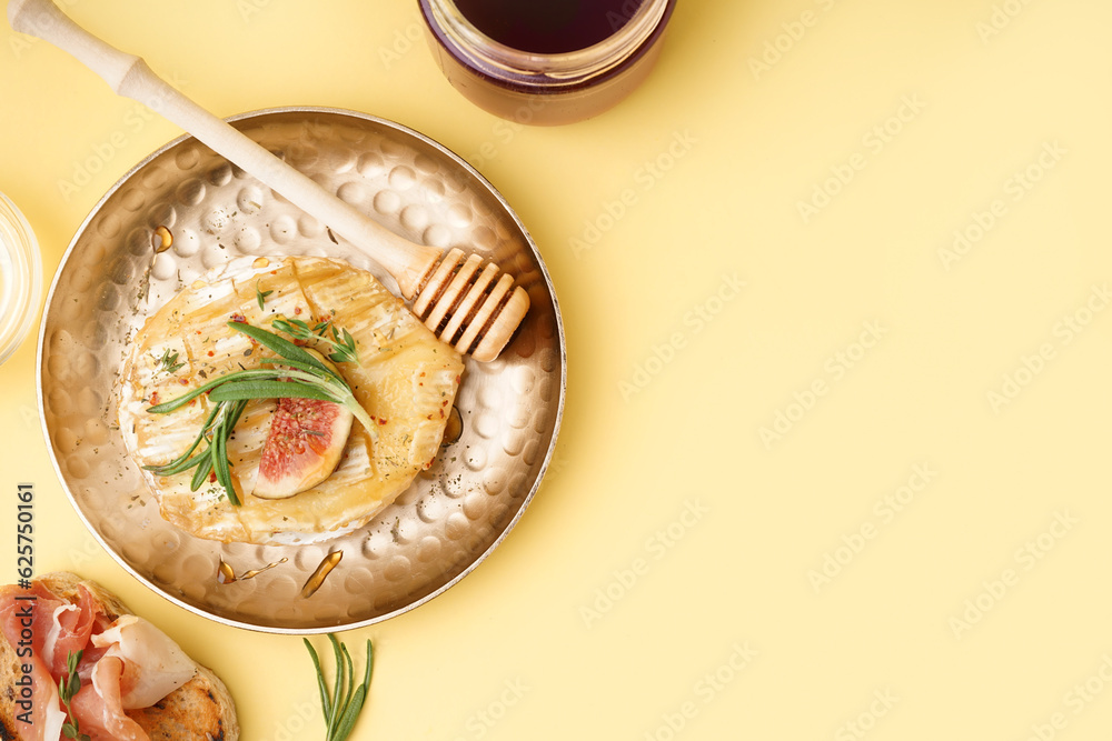 Plate with tasty baked Camembert cheese on yellow background