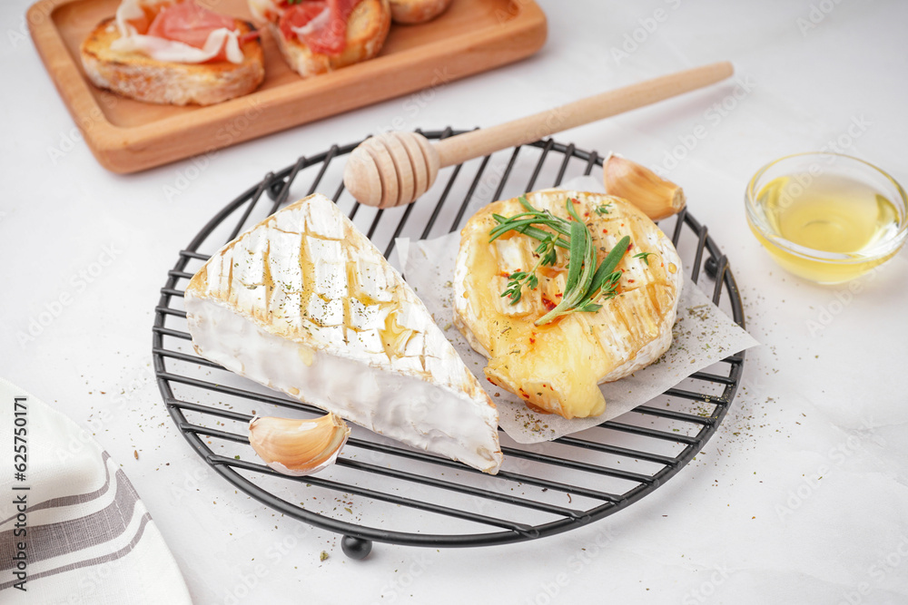 Grid with tasty baked Camembert cheese on grey background